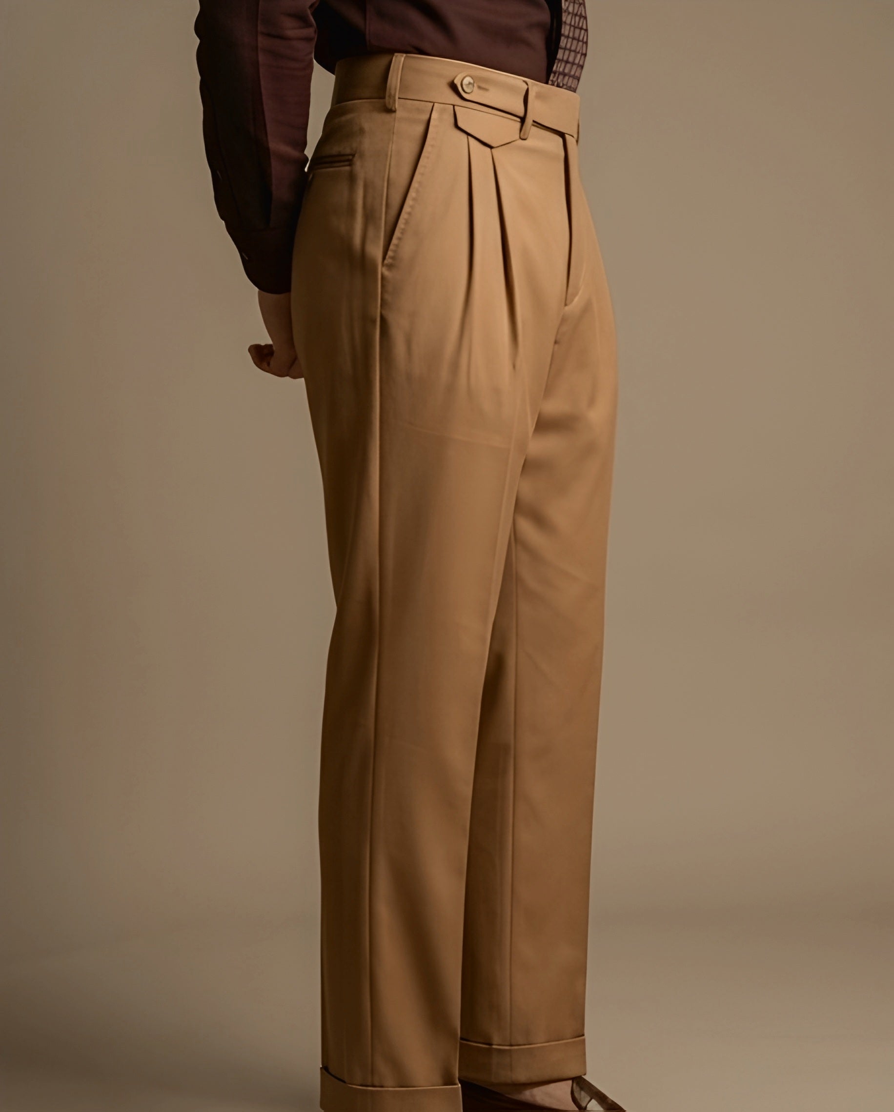 Tan pleated pants worn by a person on a beige background
